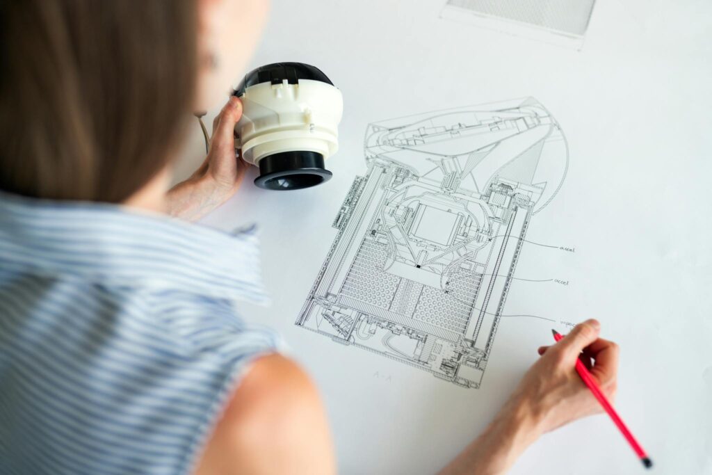 Female engineer studying a detailed technical blueprint at her workspace. Concept of design and innovation.